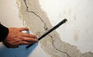 A wall with a large crack is being inspected by a professional in Anaheim, CA